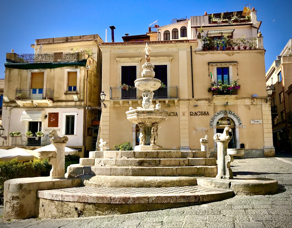 fontaine en béton blanc devant le bâtiment en béton brun pendant la journée