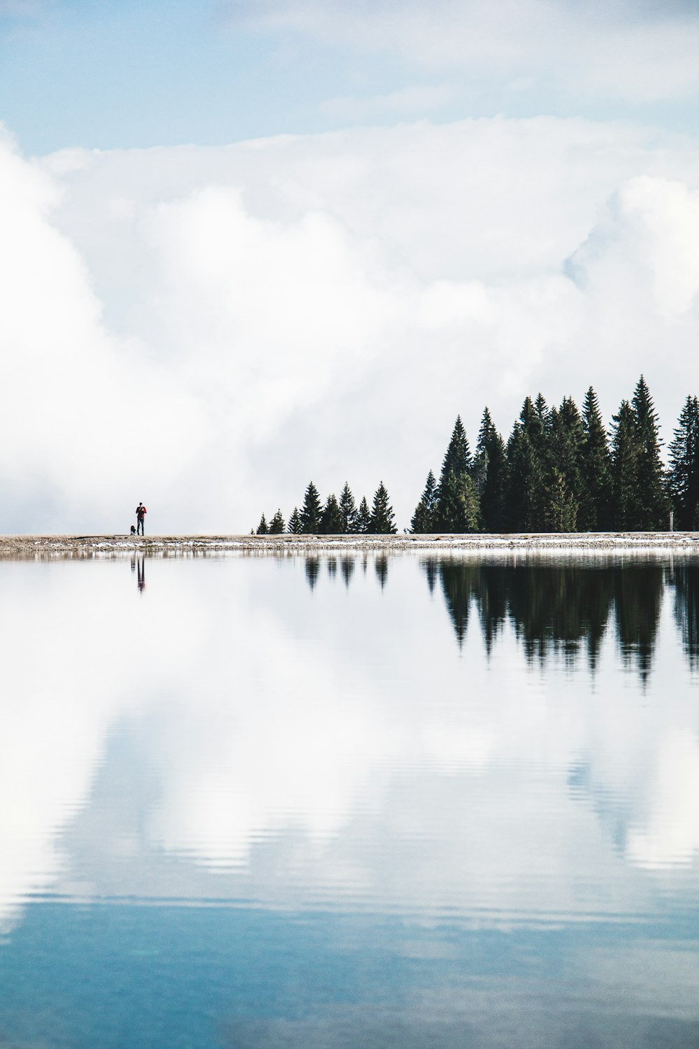 Persona in piedi sul molo vicino al lago durante il giorno