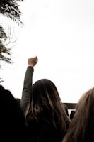 Close-up of a hand blowing a whistle with a blurred crowd in the background showing solidarity.