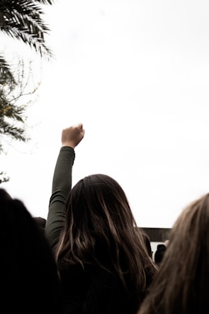 Close-up of a hand blowing a whistle with a blurred crowd in the background showing solidarity.