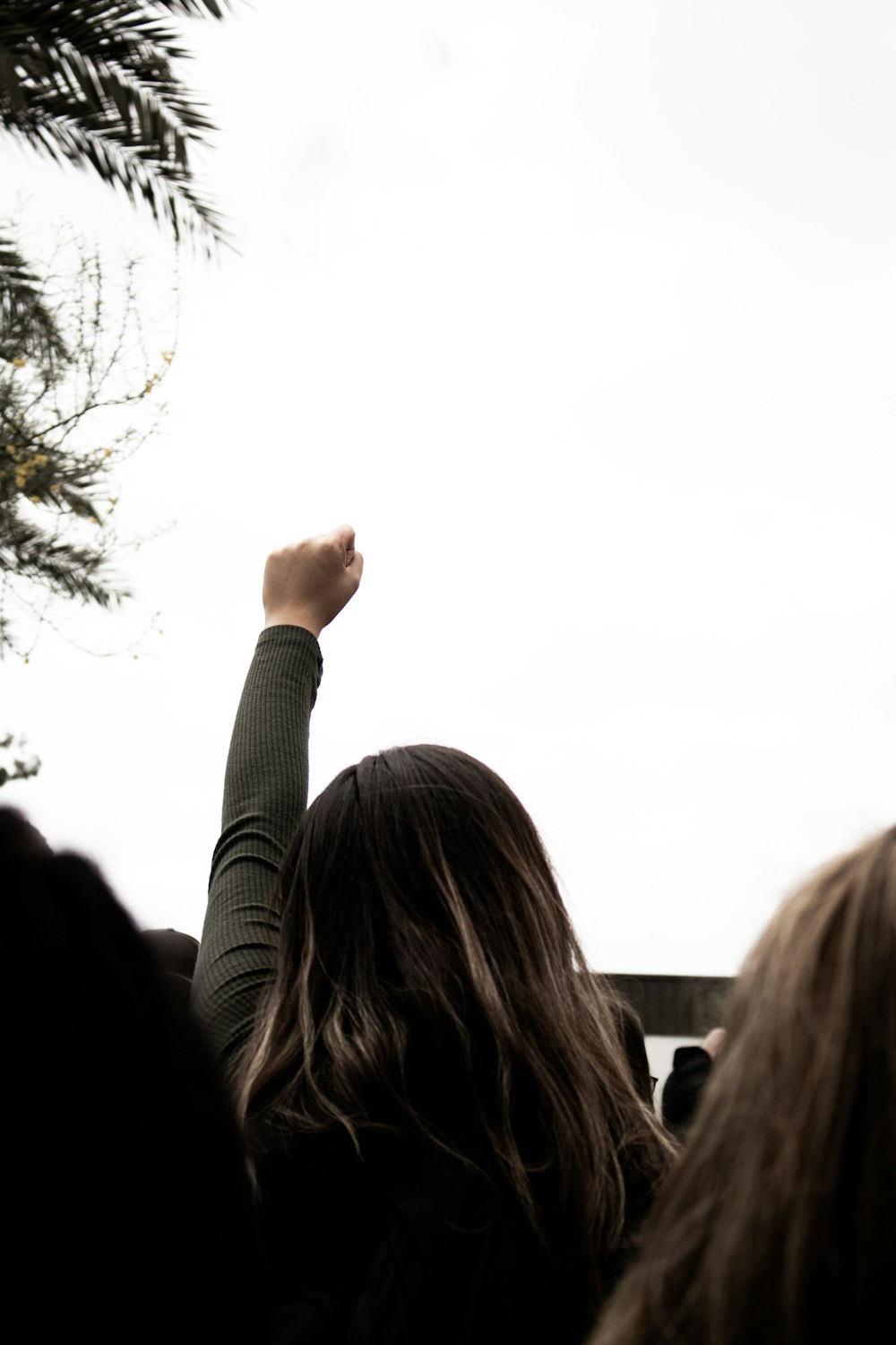 Mujer con suéter gris levantando la mano izquierda