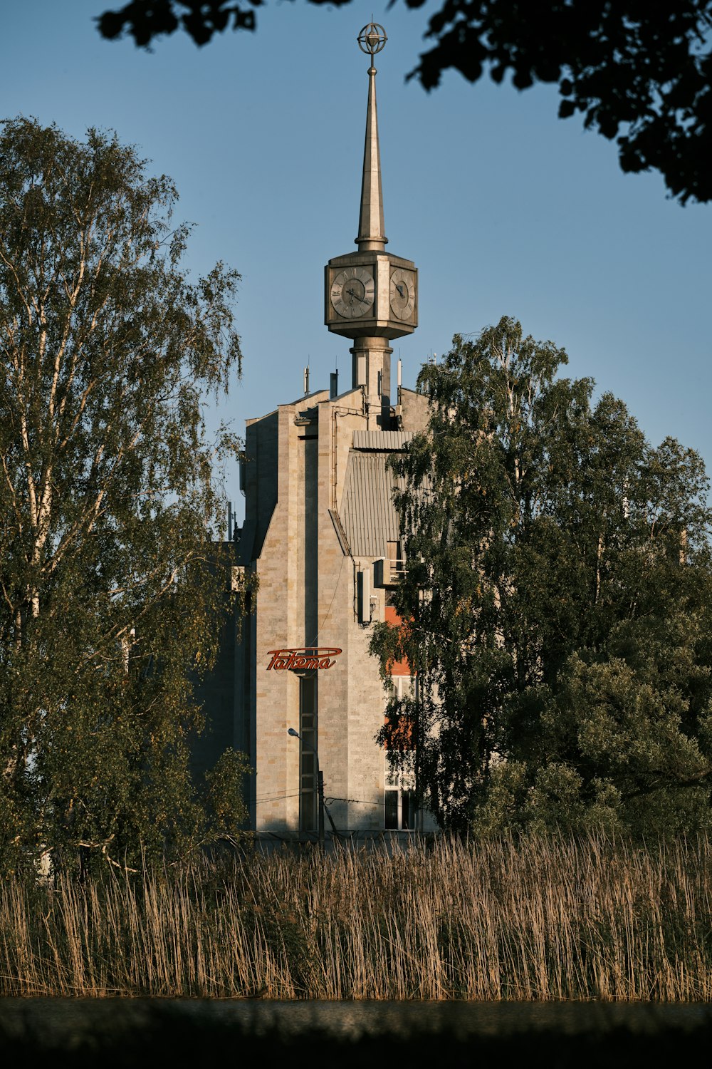 brown concrete building near green trees under blue sky during daytime