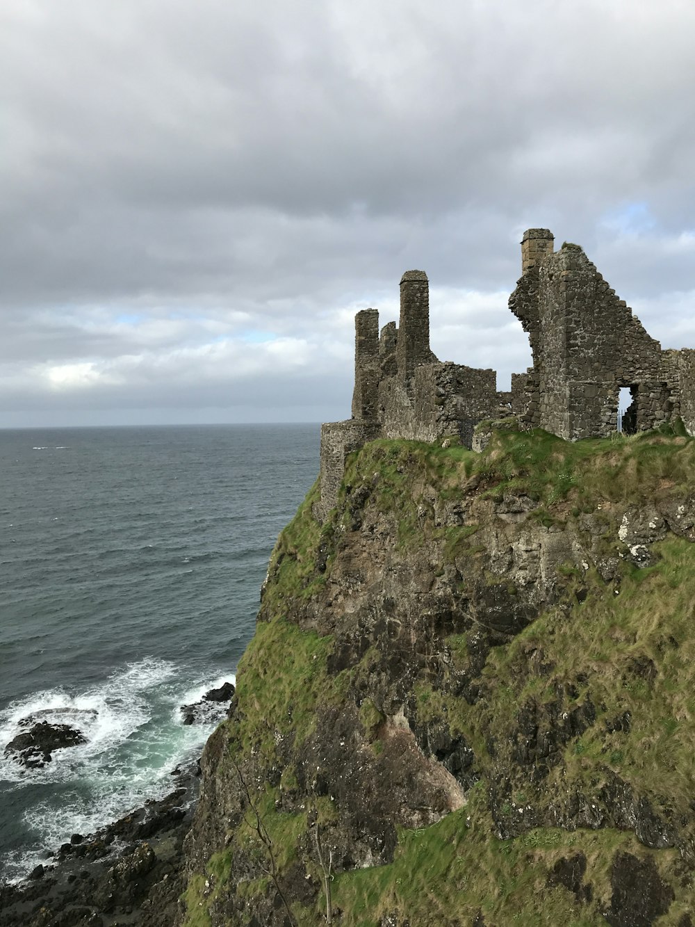 gray concrete castle on cliff near body of water during daytime