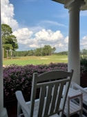 A classic rocking chair on a porch, surrounded by greenery and soft morning light.