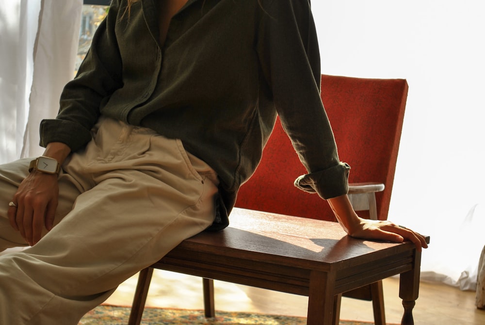 man in black long sleeve shirt and brown pants sitting on red couch