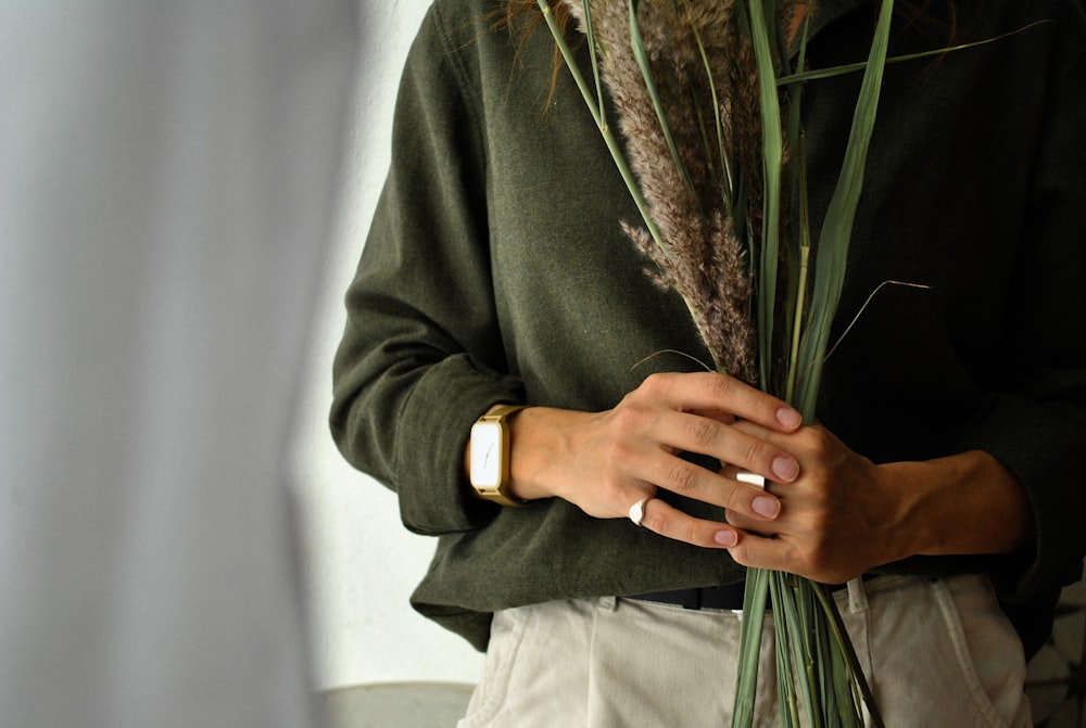 person in black long sleeve shirt holding green plant