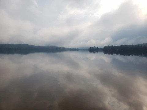 A calm lake reflecting a cloudy sky, evoking peace amid turmoil.