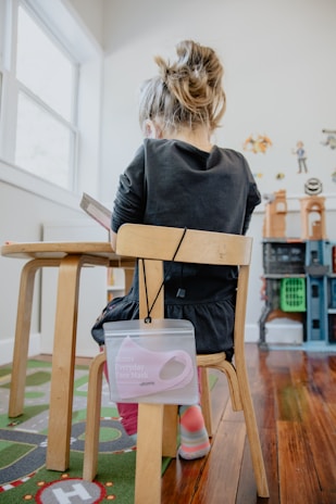 Happy child engaged in a puzzle from an activity book at a sunny kitchen table.