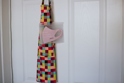 A vibrant apron splattered with multiple colors hanging in a cozy kitchen.