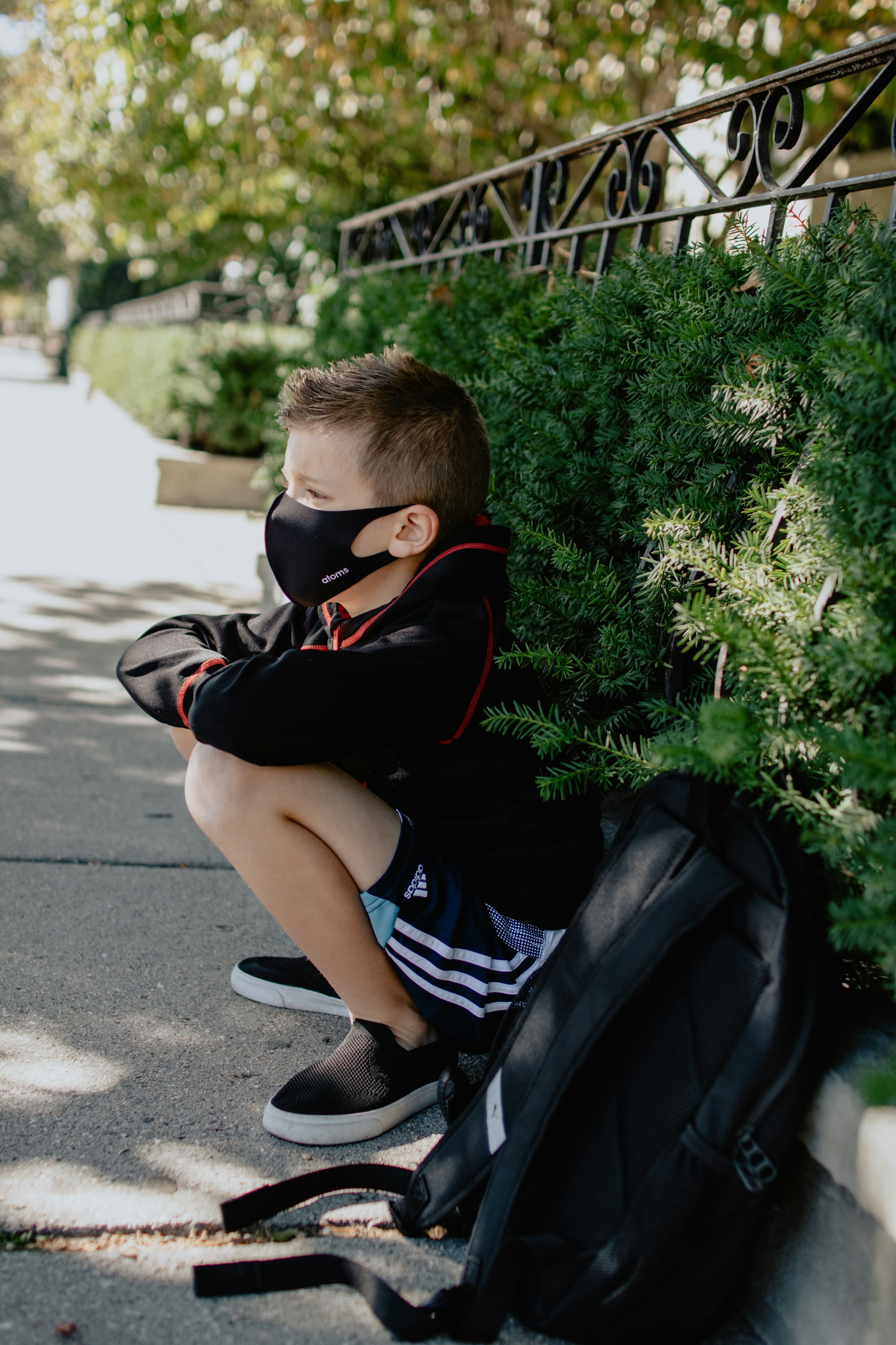 Boy sitting on sidewalk with mask on
