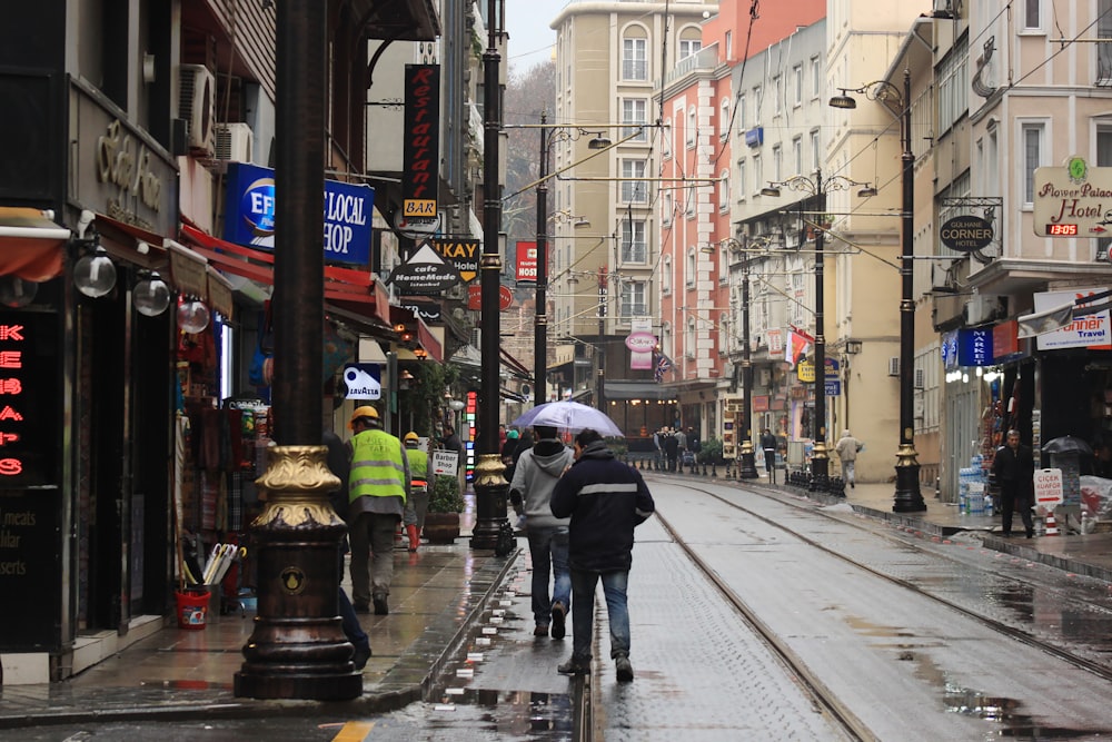 person in black jacket and black pants holding umbrella walking on sidewalk during daytime