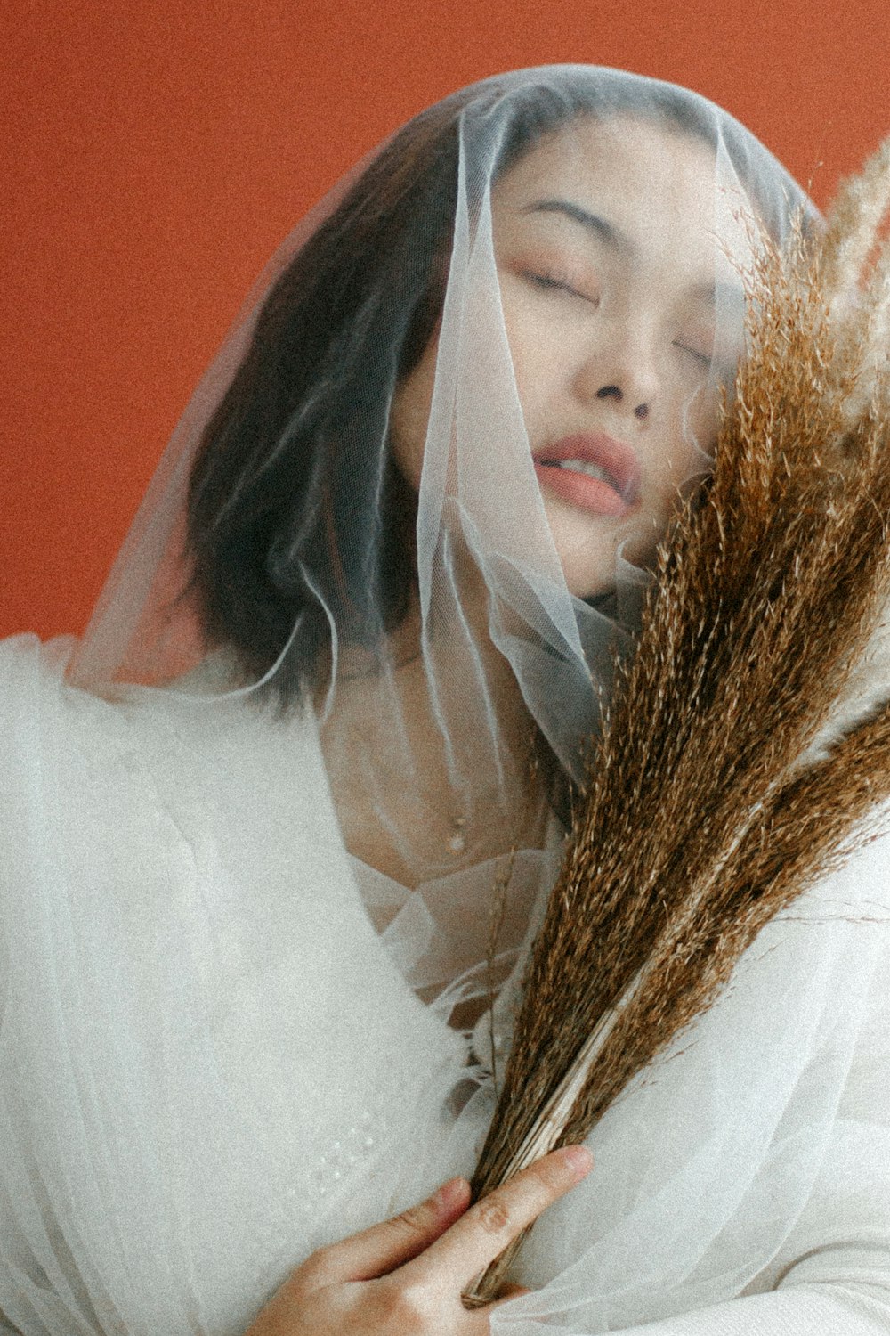 woman in white dress covering face with white textile