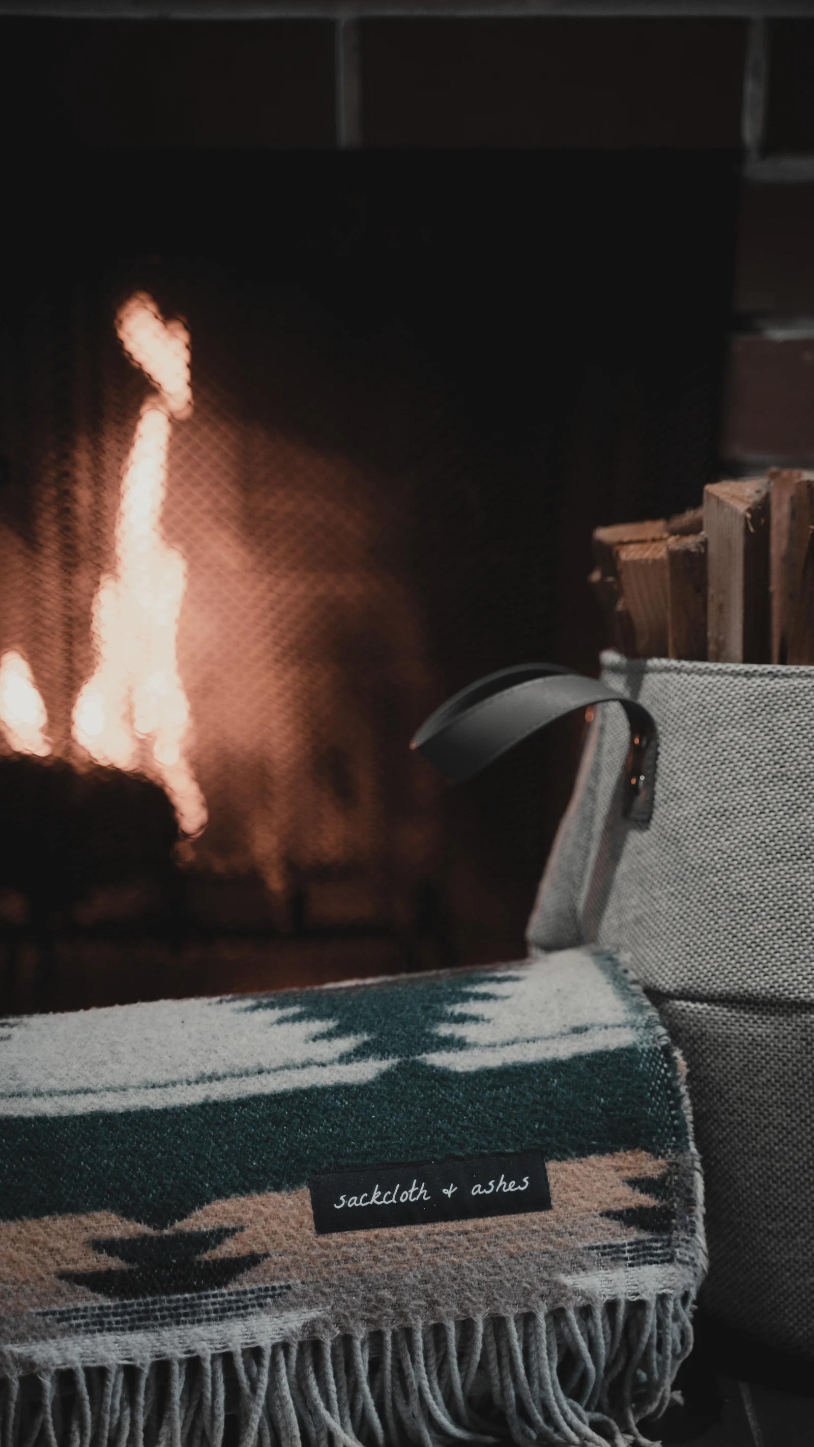 A dark leather armchair standing beside a lit fireplace.