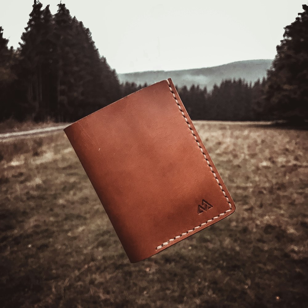 braune Leder-Bifold-Brieftasche auf braunem Feld tagsüber