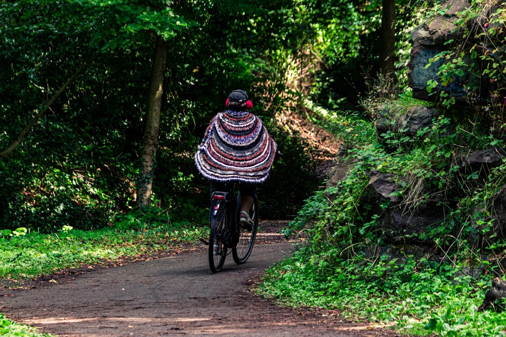 person in black and white stripe shirt riding bicycle on road during daytime