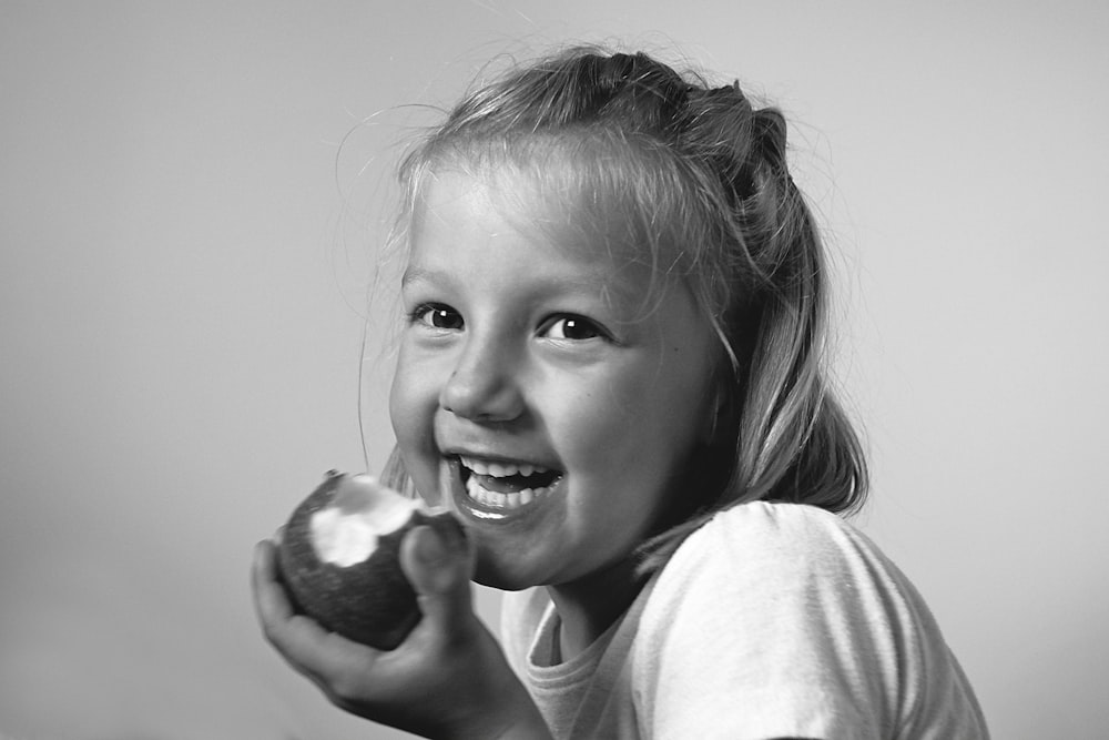 grayscale photo of girl holding round fruit