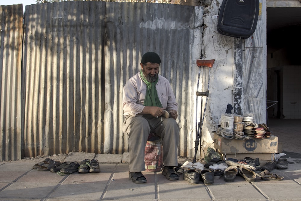 man in green dress shirt and brown pants sitting on chair