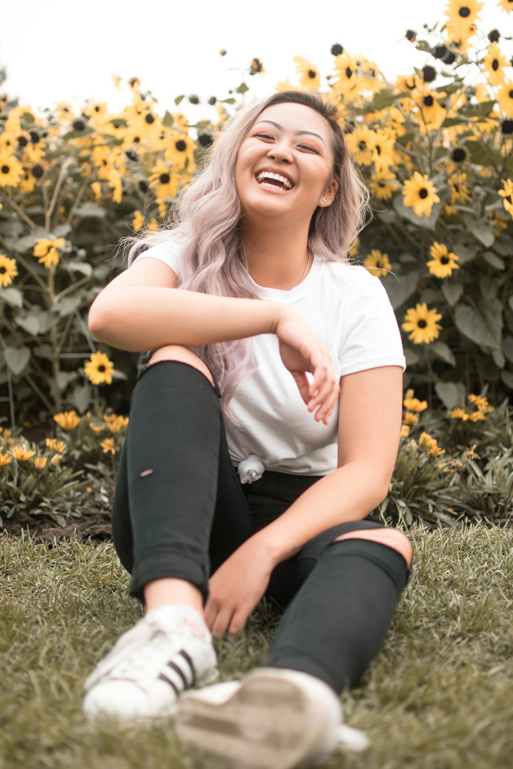 woman in white t-shirt and black pants sitting on green grass field