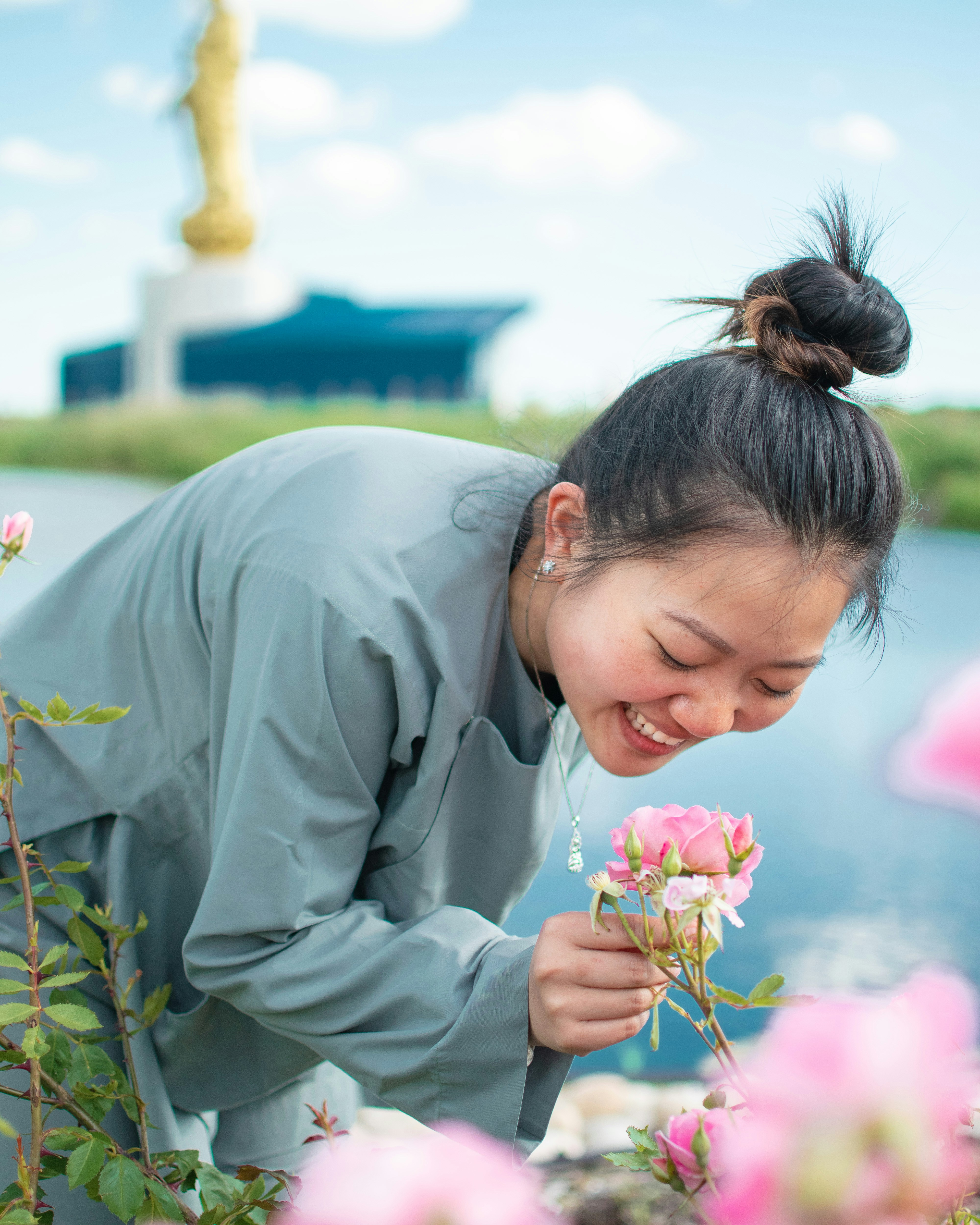 Frau in grauem Gewand, die tagsüber rosa Blume hält