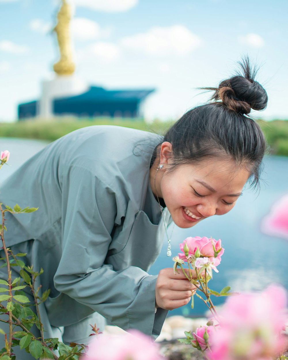 woman in gray robe holding pink flower during daytime