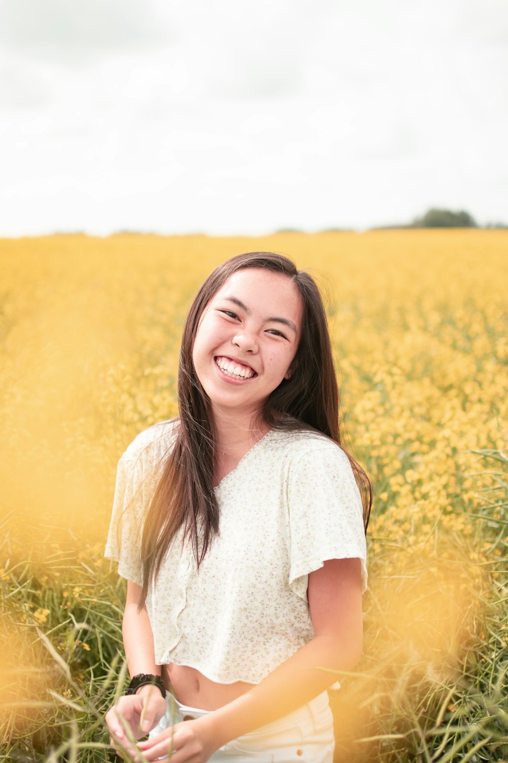 woman in white crew neck t-shirt standing on yellow flower field during daytime