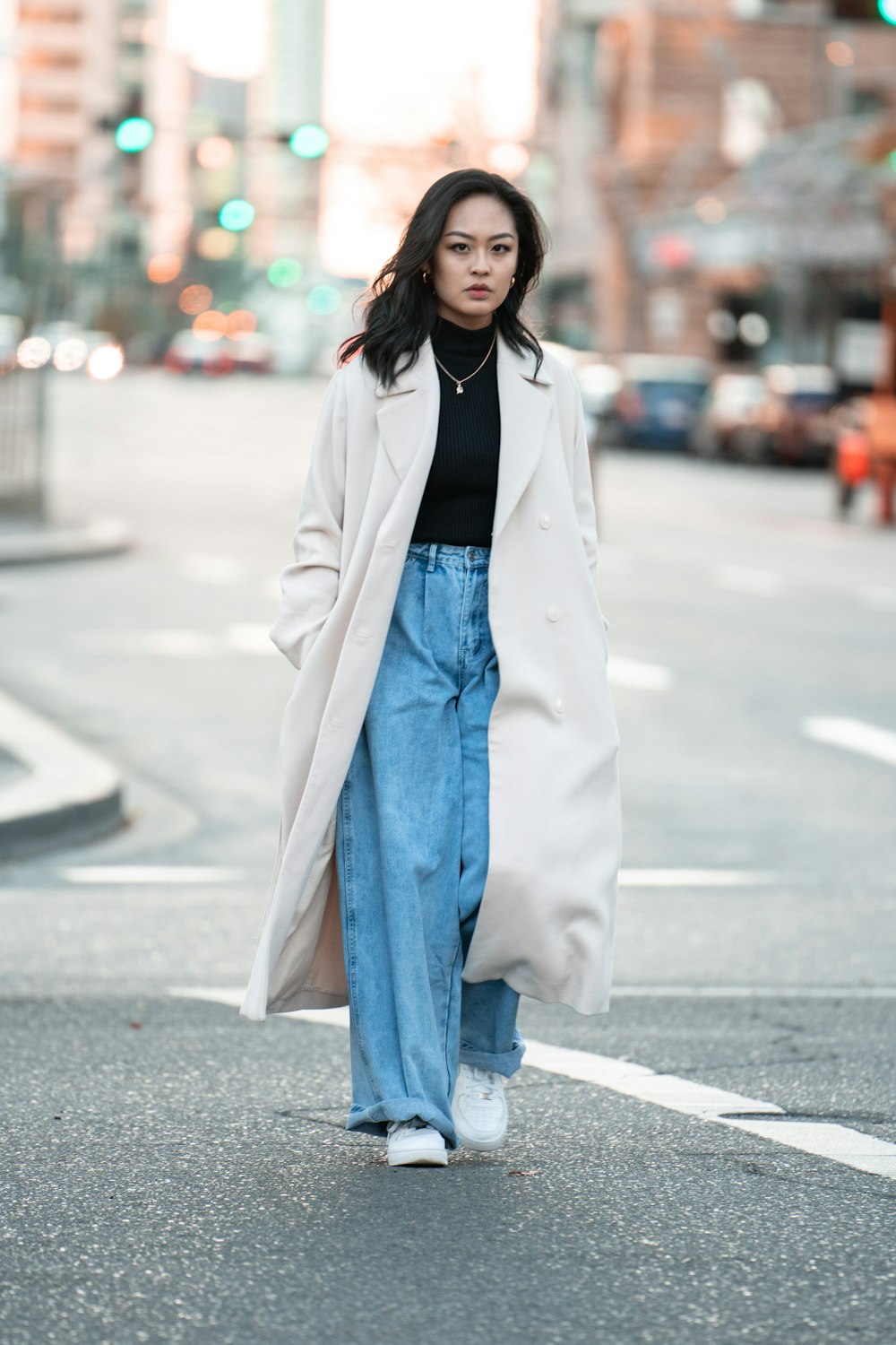 woman in white coat standing on road during daytime