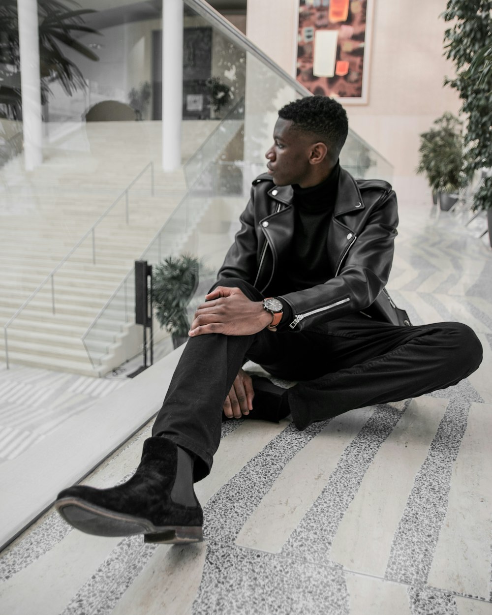 man in black leather jacket and black pants sitting on white and black checkered floor