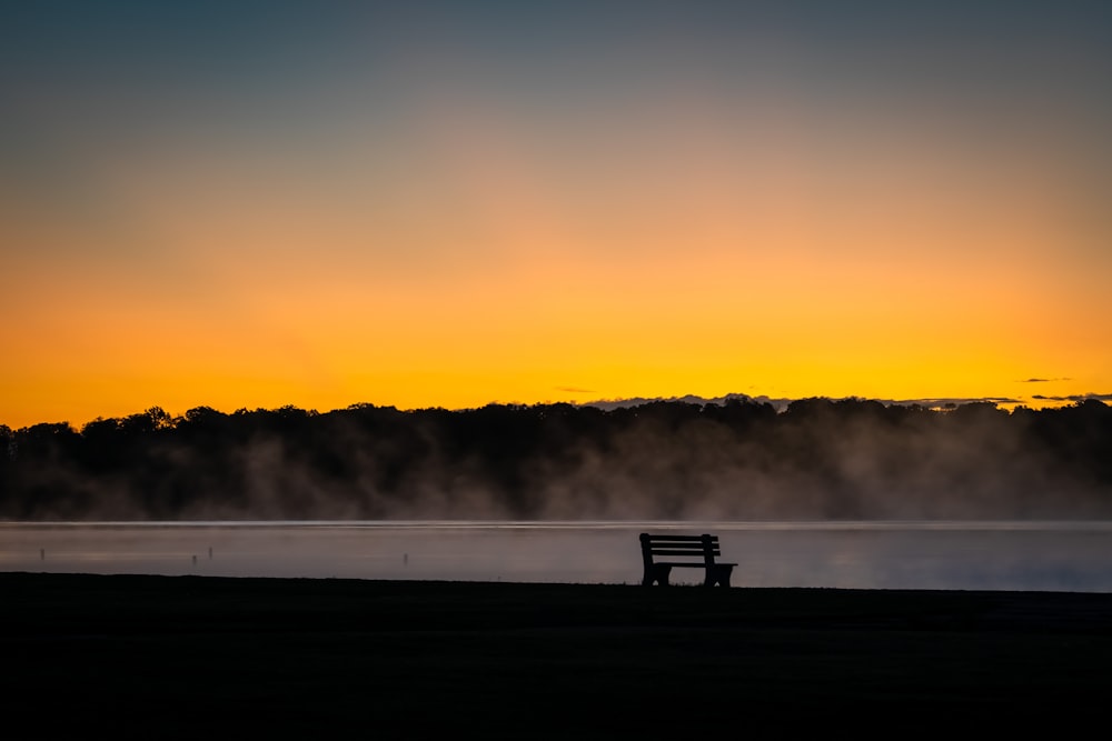 silhouette of bench on field during sunset