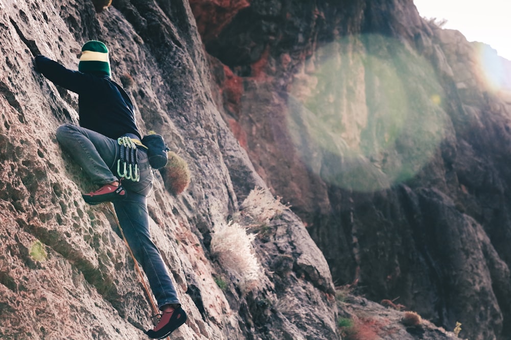 man in black jacket and blue denim jeans sitting on rock