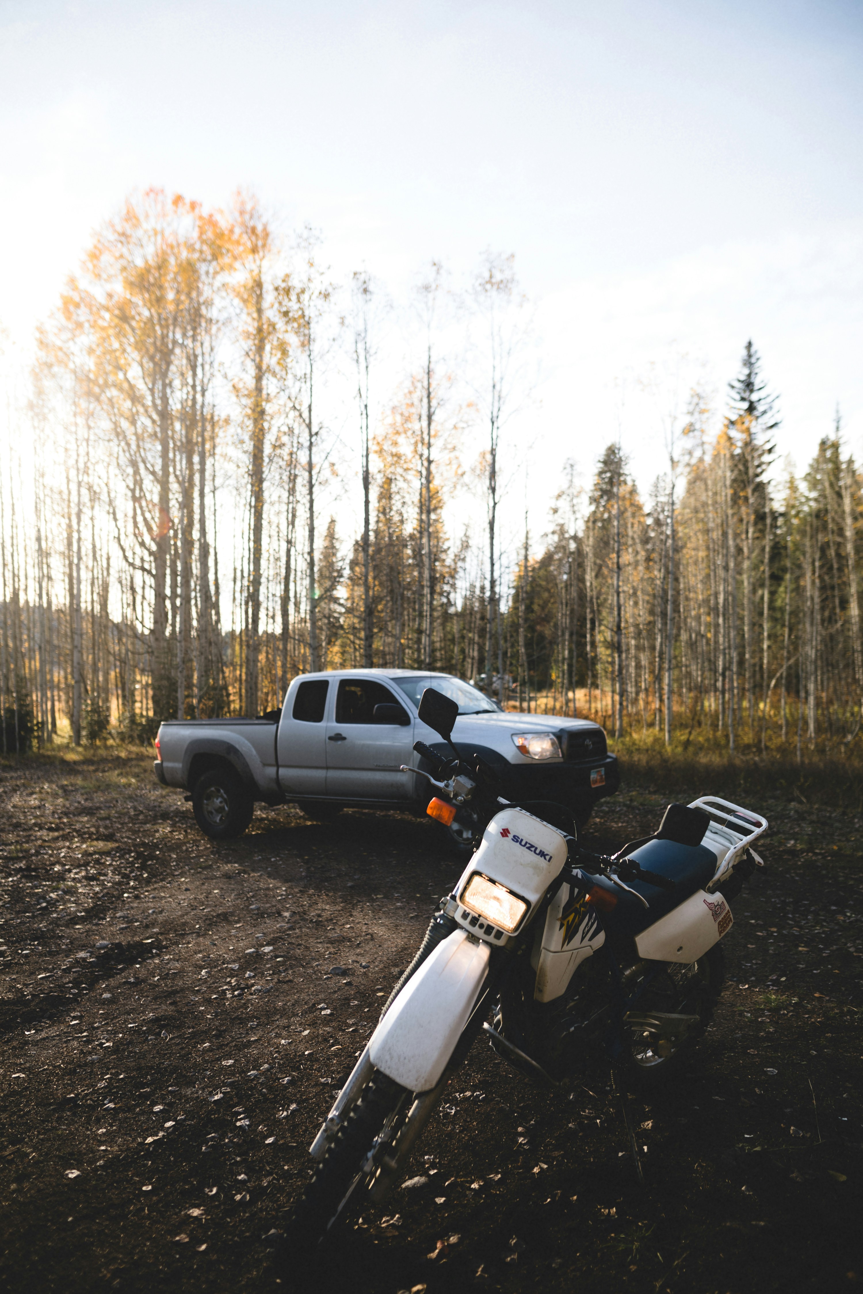 white-and-black-sports-bike-parked-on-dirt-road-near-trees-during-daytime