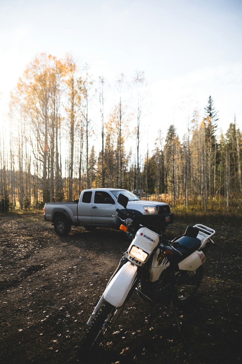 white and black sports bike parked on dirt road near trees during daytime