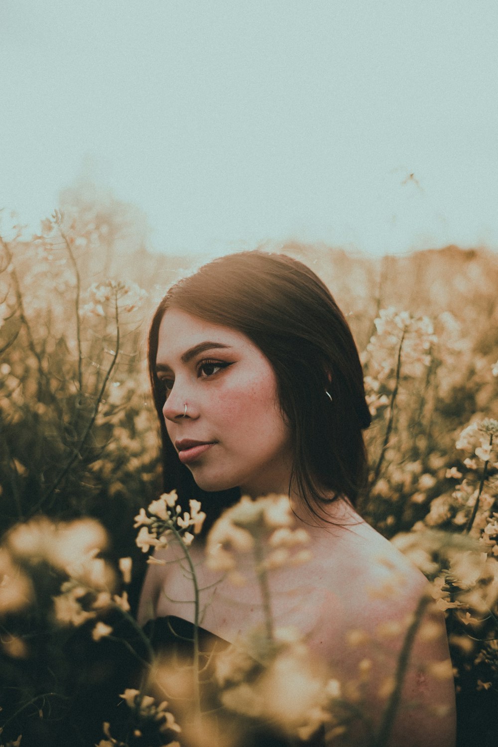 woman in white floral shirt standing near brown plants during daytime