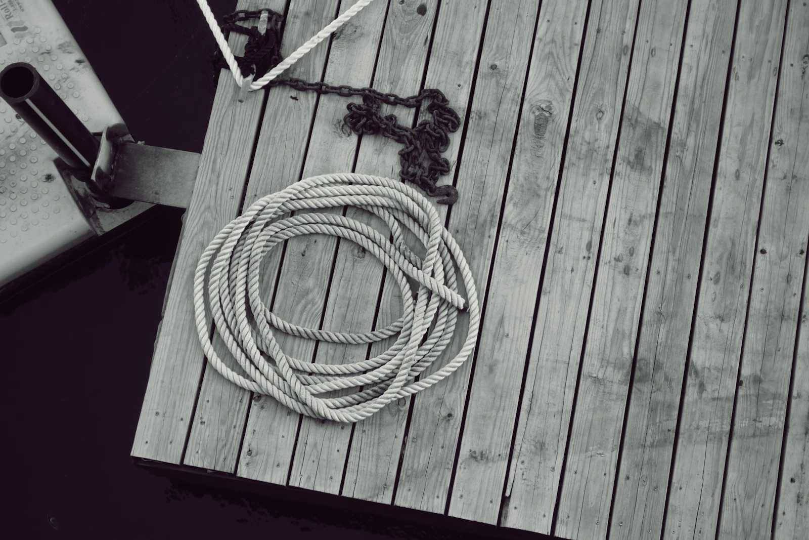 A coil of pale rope on grey weathered dock boards