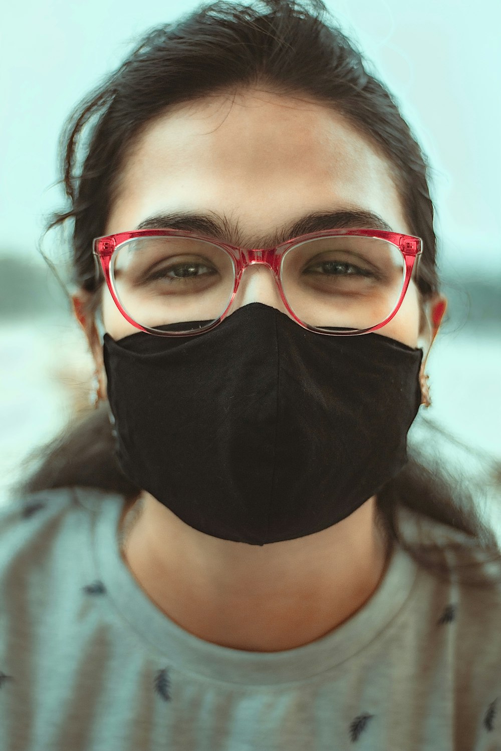 woman in red framed eyeglasses covering her face with black scarf