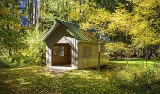 A cozy wooden gazebo surrounded by lush vegetation and a small playground nearby.