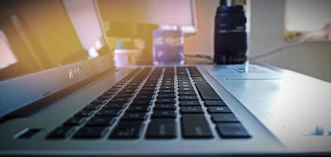 Close-up of a sleek ASUS laptop open on a wooden desk with soft natural light.