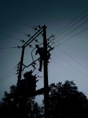 silhouette of electric post under cloudy sky during daytime