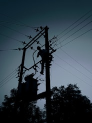 silhouette of electric post under cloudy sky during daytime