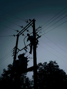 silhouette of electric post under cloudy sky during daytime