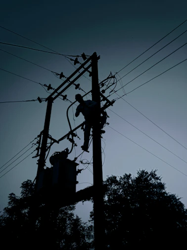 silhouette of electric post under cloudy sky during daytime
