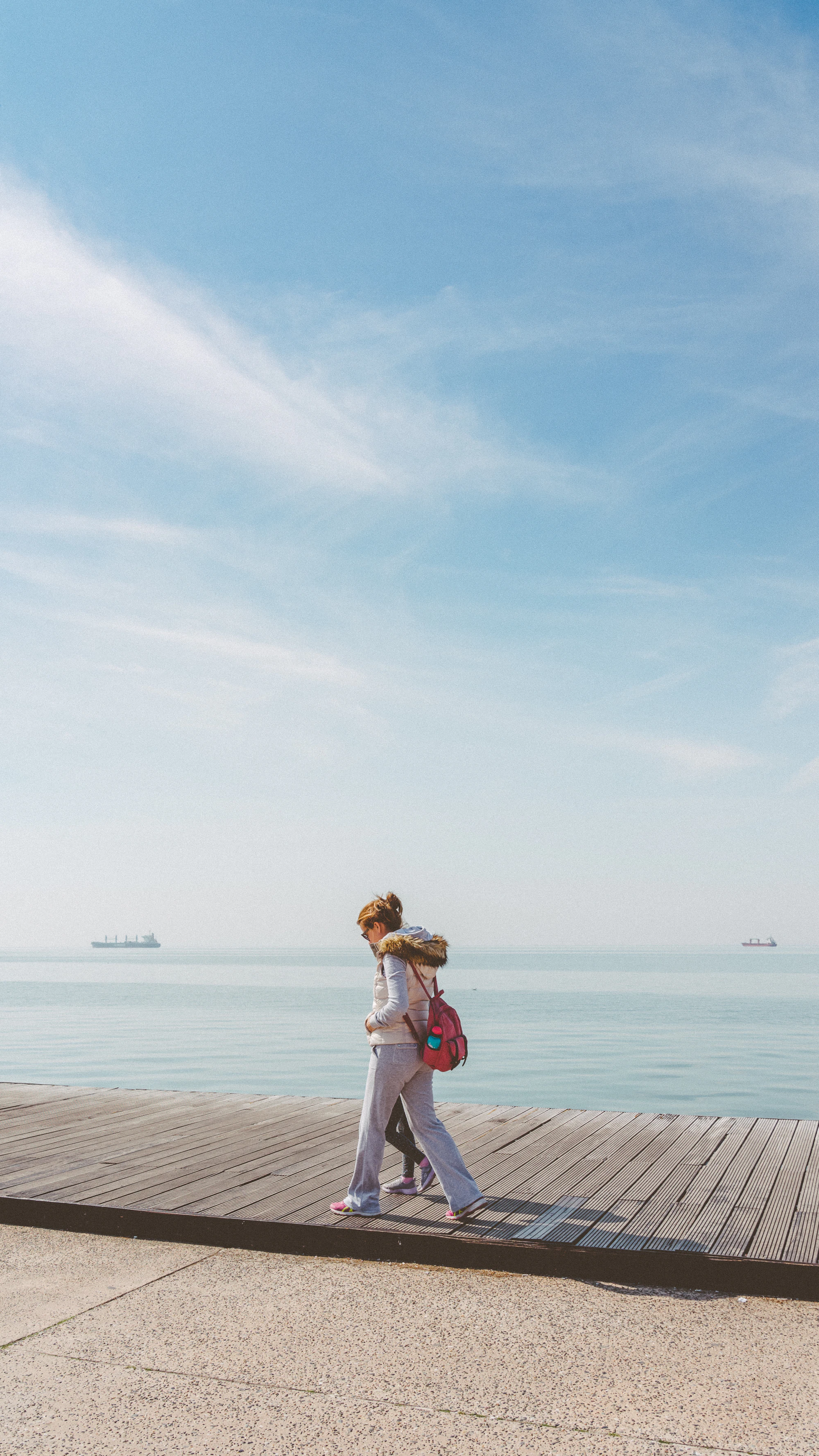 A woman in a white linen dress walking on a quiet Skyrian beach with pale sand and clear turquoise water