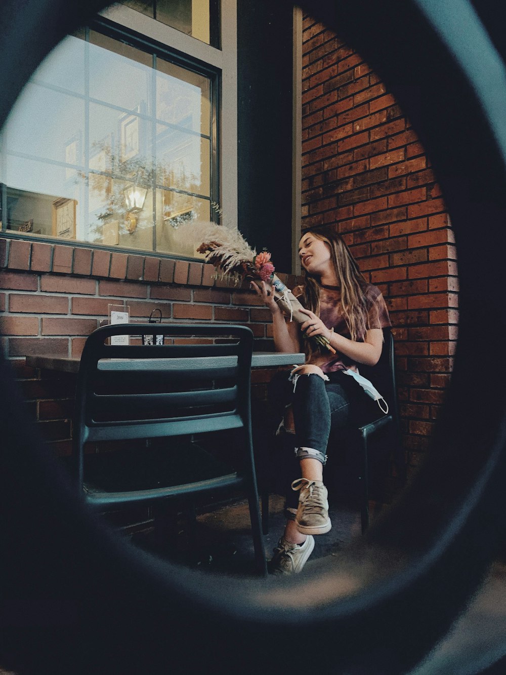 woman in black jacket and black pants sitting on black wooden bench