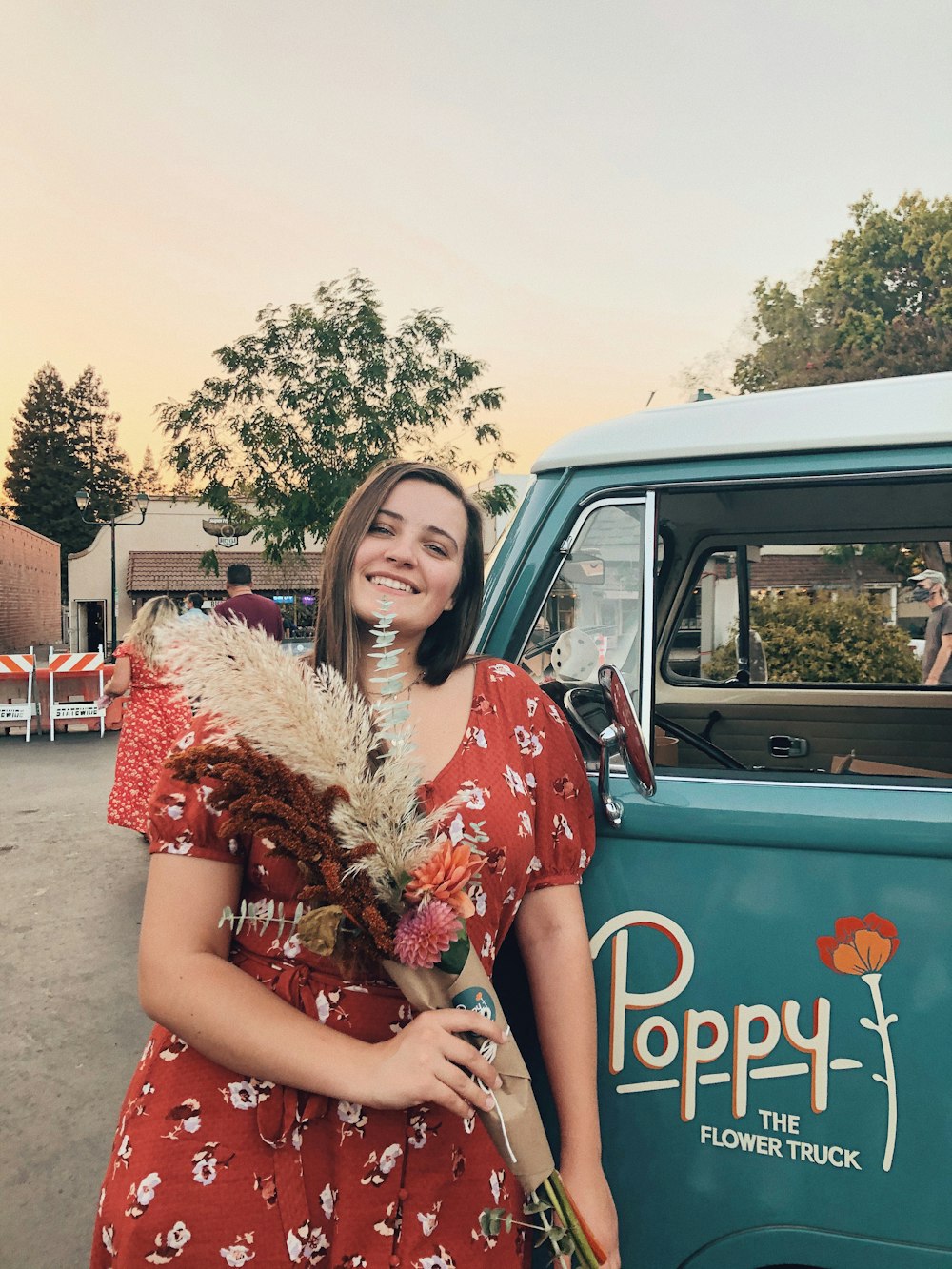 woman in red and white floral dress leaning on blue car