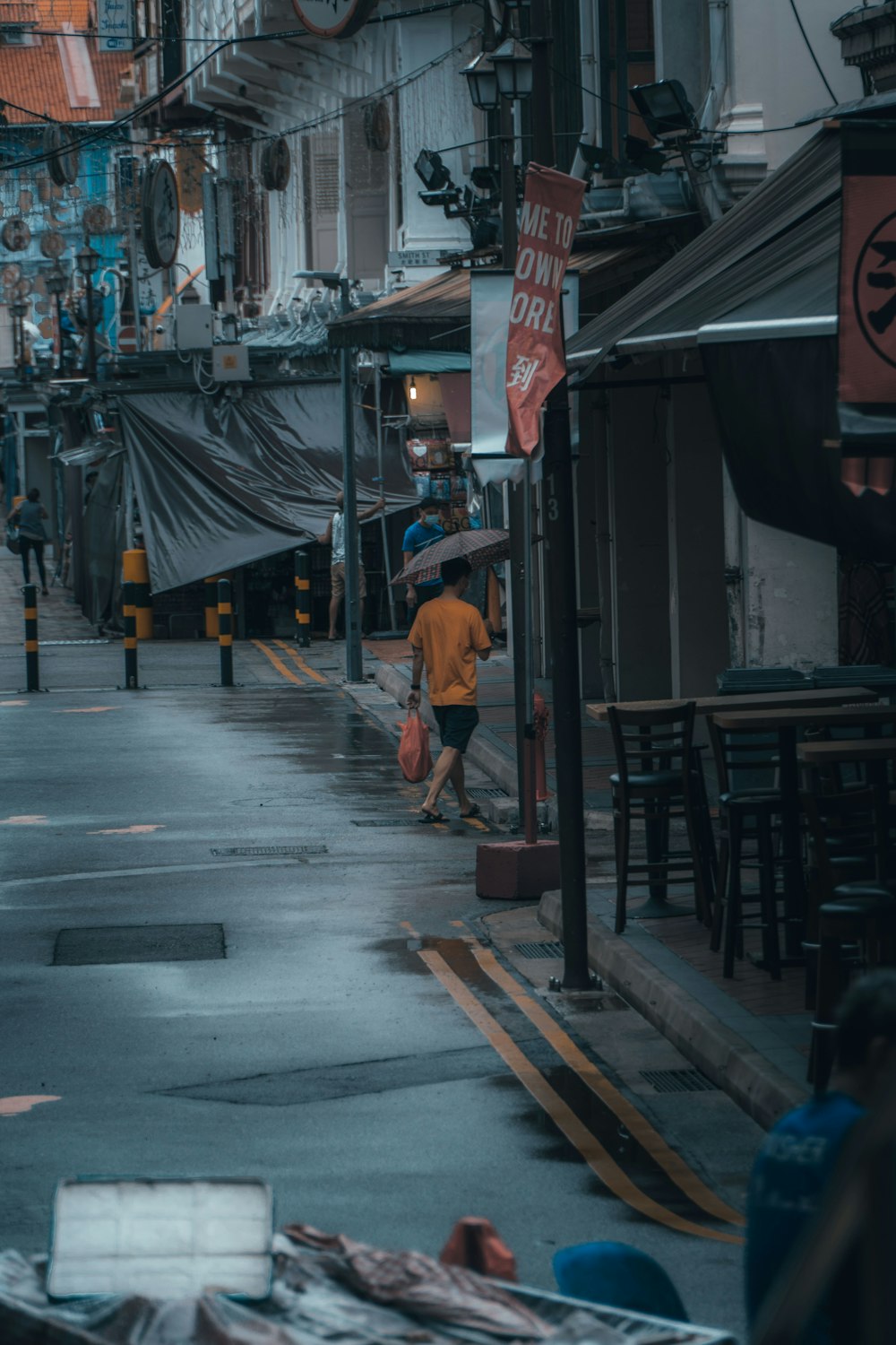 man in orange t-shirt walking on street during daytime