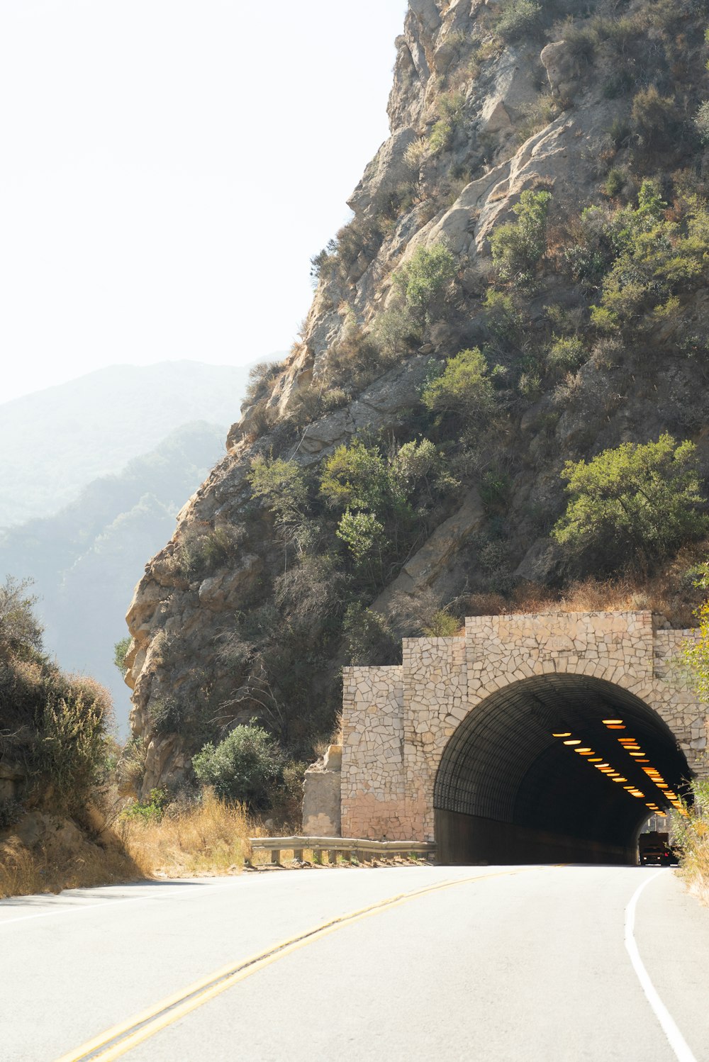a car driving through a tunnel on a mountain road