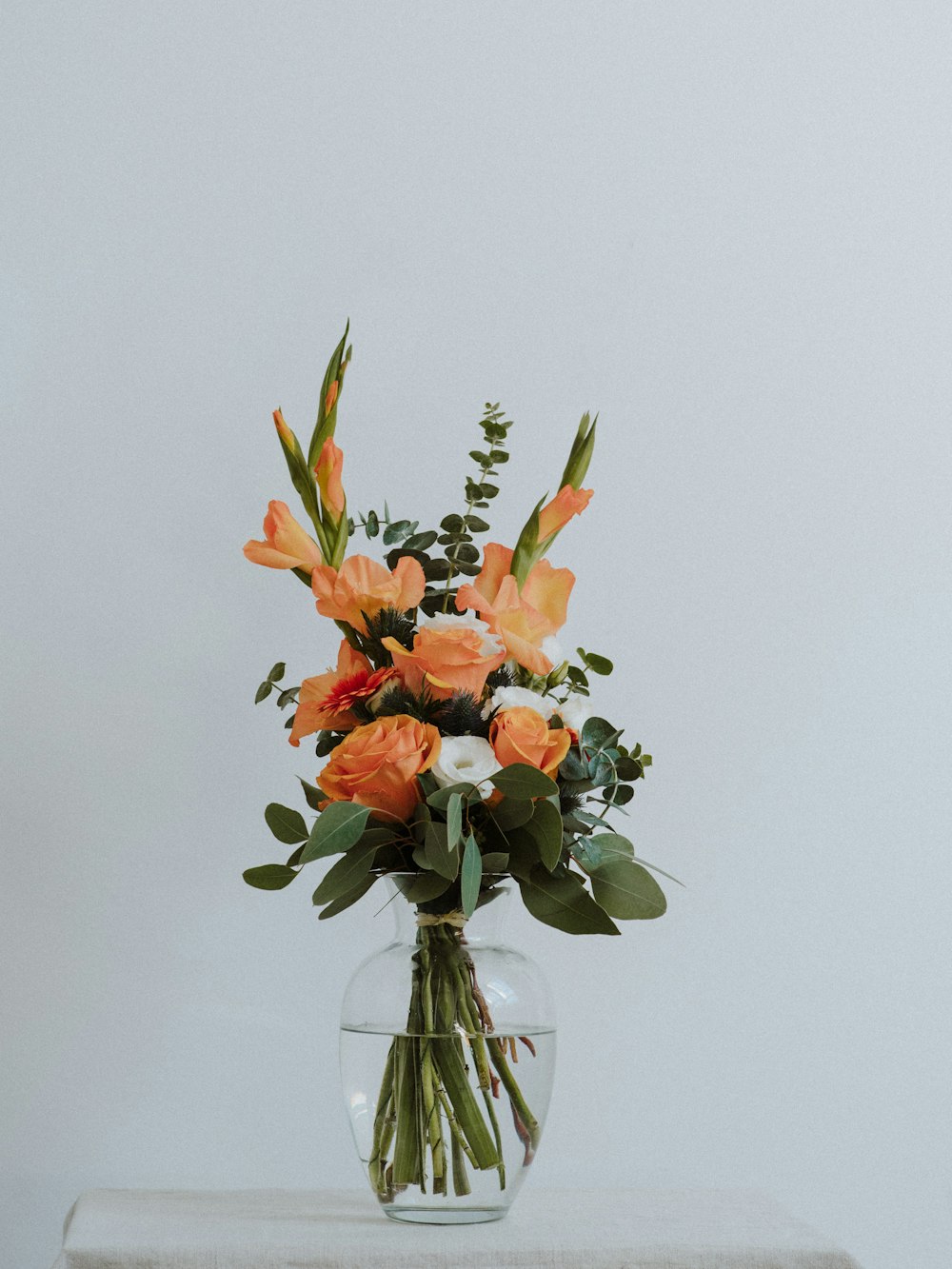 orange flowers in clear glass vase