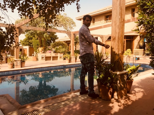A friendly gardener and pool technician discussing plans in a lush backyard.