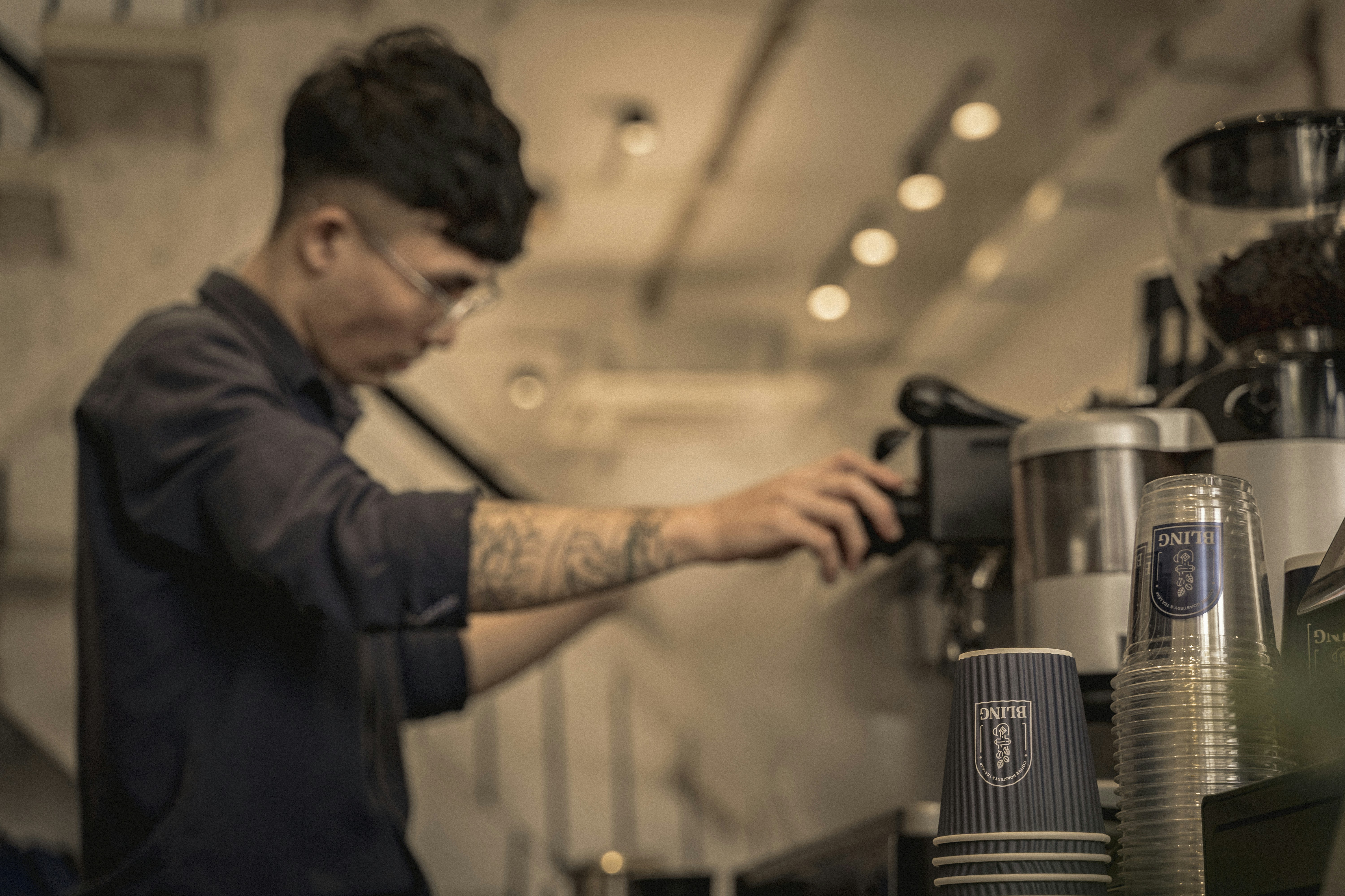 Barista with tattoos working at an espresso machine