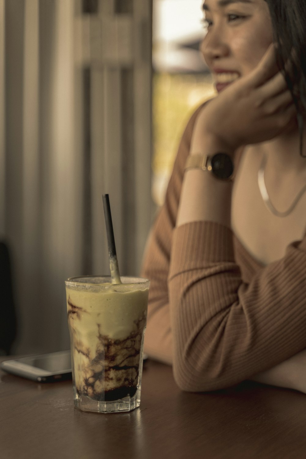 woman in brown long sleeve shirt holding white plastic cup