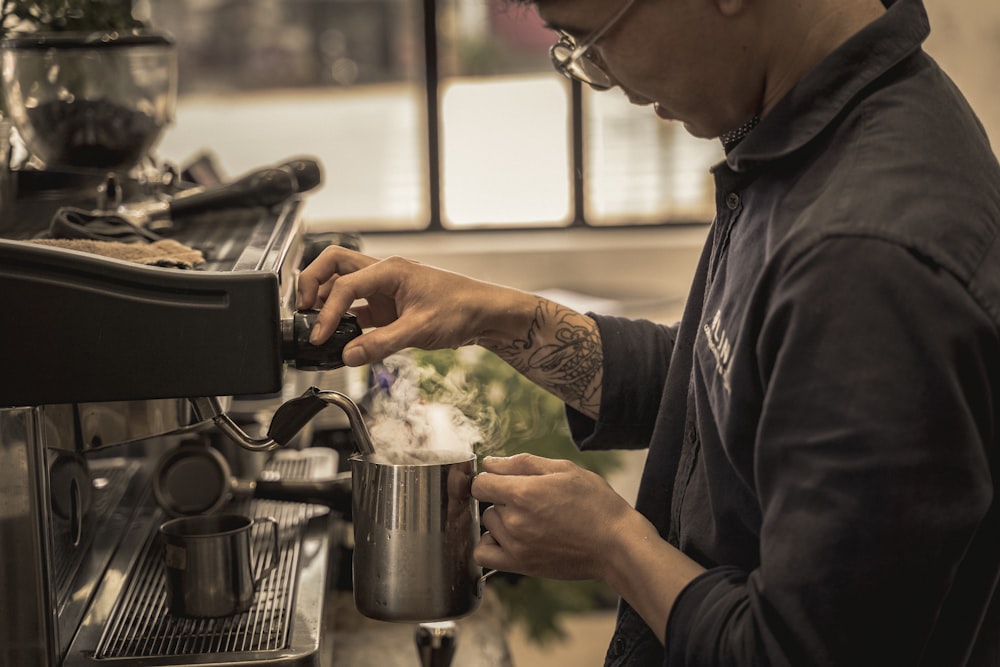 man in black long sleeve shirt pouring coffee on black ceramic mug